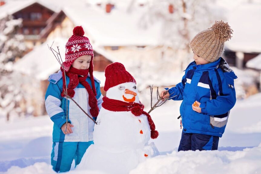 children in snow building snowman